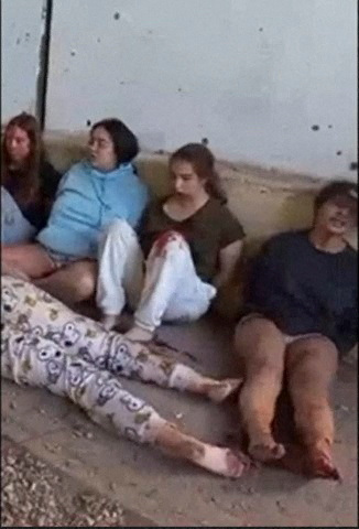 Female hostages who are Israeli soldiers Liri Albag, Agam Berger, Daniela Gilboa and Naama Levy sit on the ground while captive by Hamas