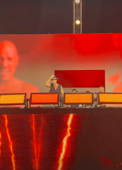 a man in a hat stands in front of a large screen