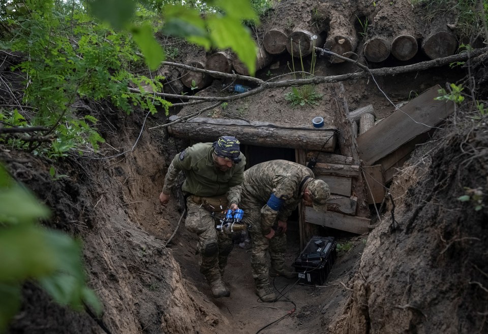 A Ukrainian serviceman of the attack drones battalion carries a drone before it flies, near a Russian border in the Kharkiv region