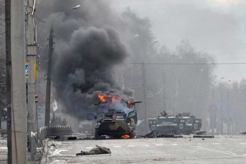 A soldier’s body lies near a burning Russian truck