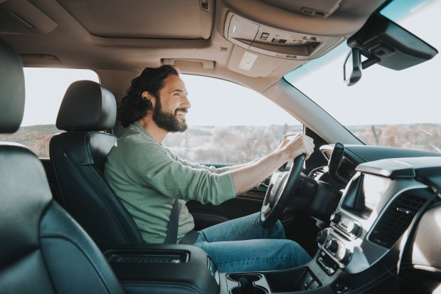 A smiling man driving a car.