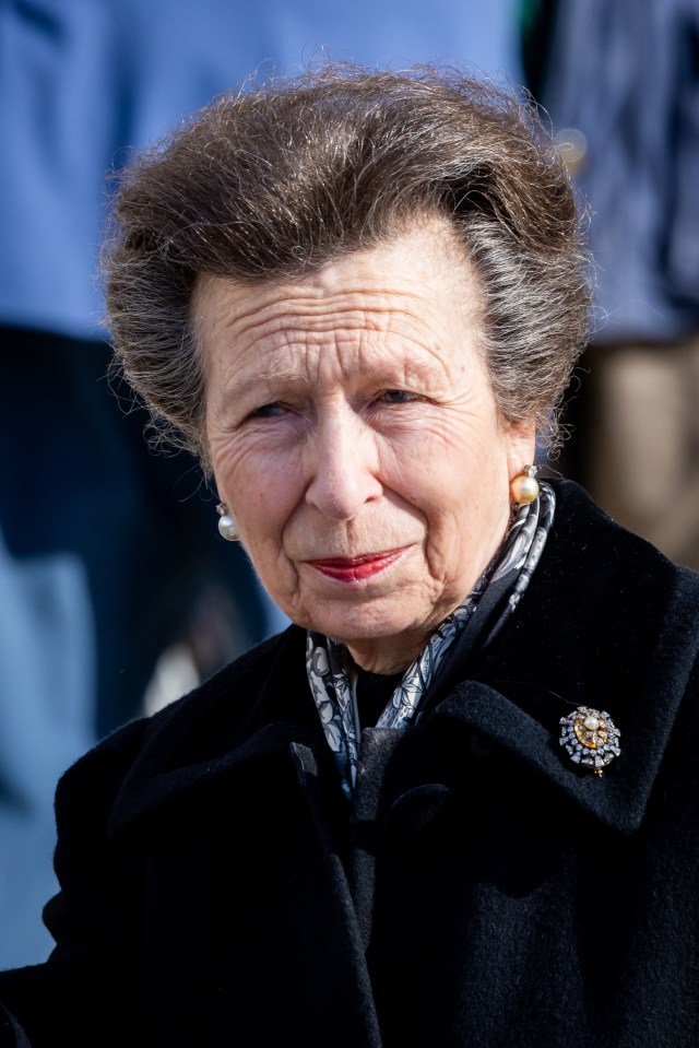 an older woman wearing a black coat and a brooch