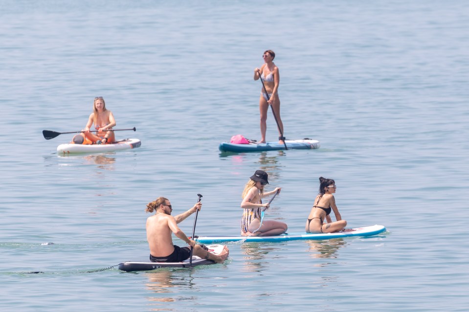 Paddle boarders enjoy the warm weather on Brighton Beach on Tuesday morning