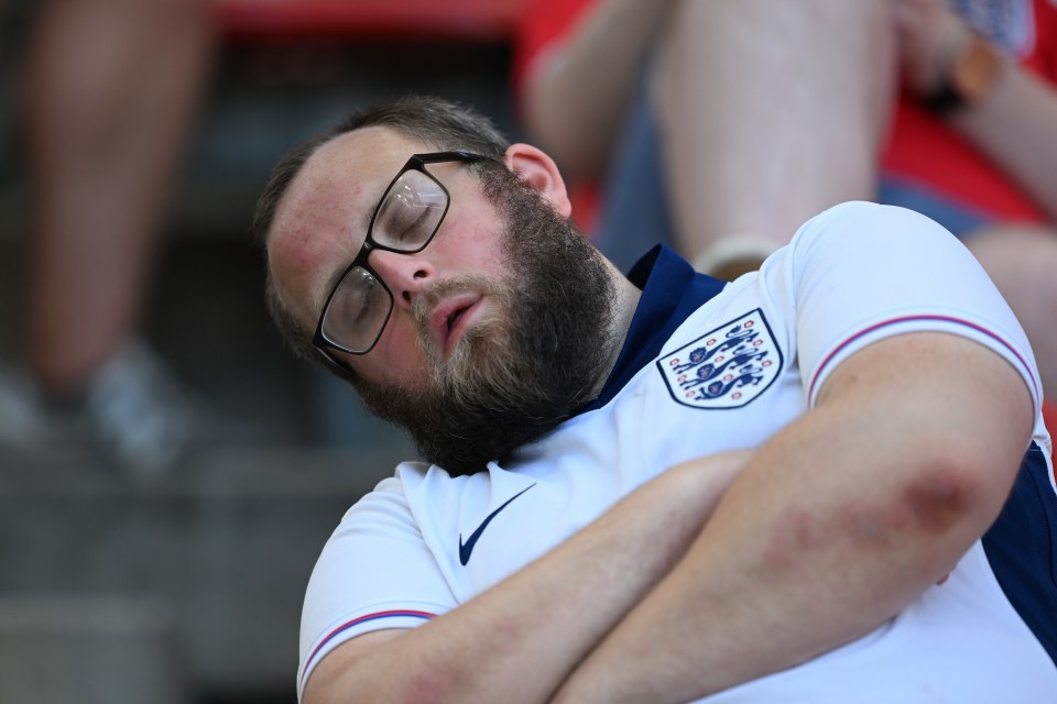 a man with glasses and a beard is sleeping in a stadium