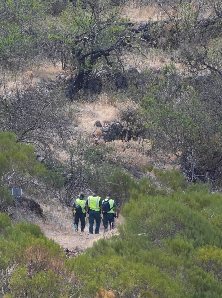 a group of police officers are walking down a dirt path