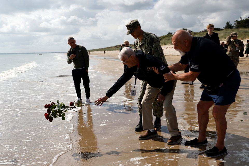 American WWII veteran Bill Wall throws roses into the water during a wreath-laying ceremony at Utah Beach, Normandy