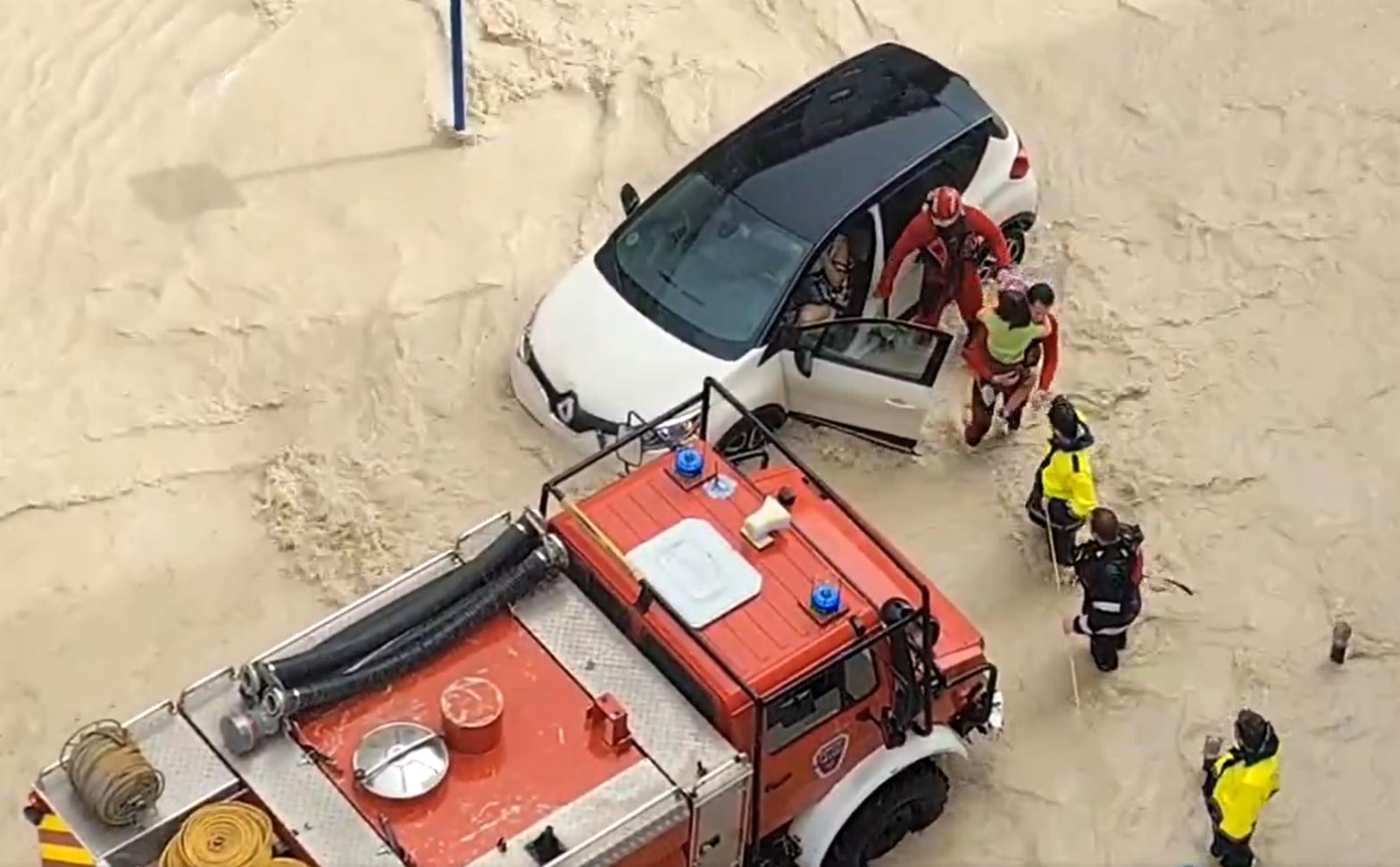 Rescue workers use a rope to rescue a family from their trapped car