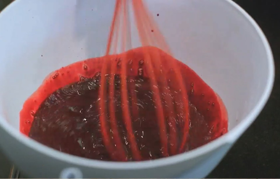 red liquid is being poured into a white bowl