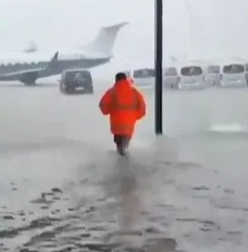 Airport workers seen wading through knee-high floods