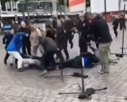 The man in blue begins punching someone on the ground