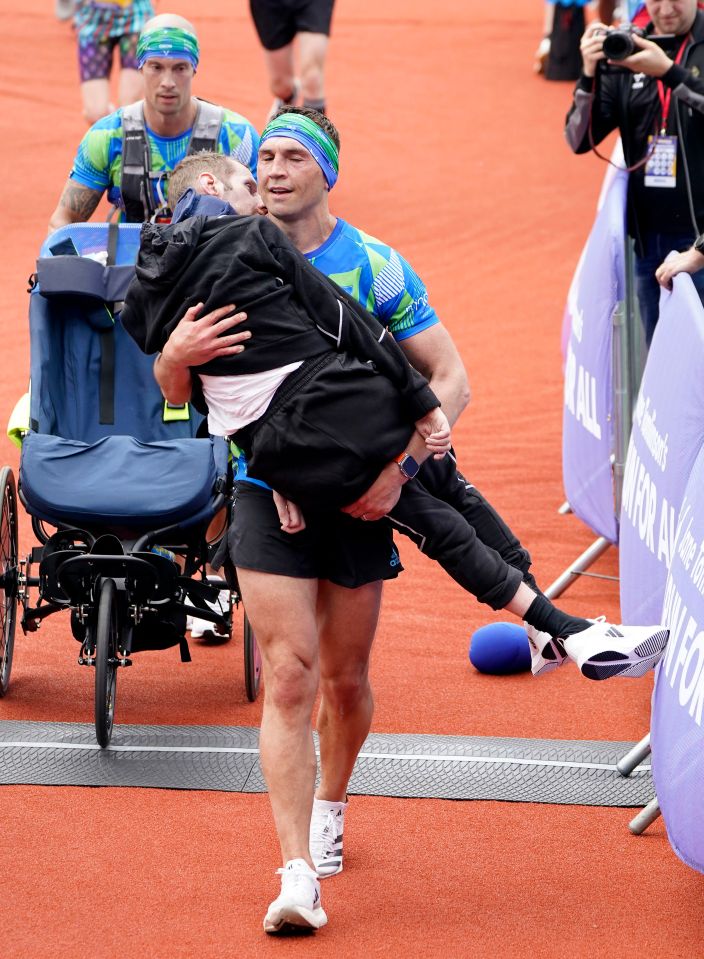 a man is carrying a child in his arms in front of a sign that says work for all