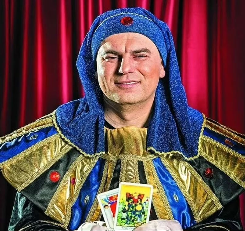 a man in a blue and gold costume is holding tarot cards