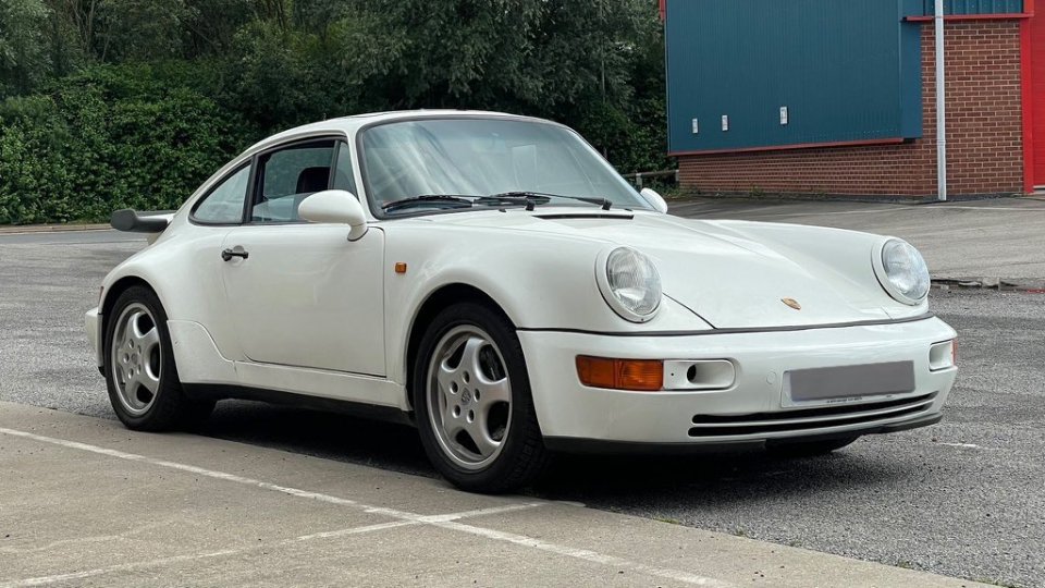 a white porsche is parked in a parking lot