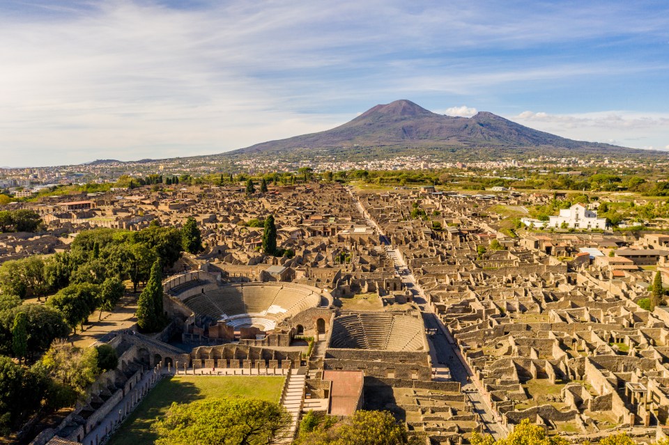 An aerial view of the remains of Pompeii as Vesuvius towers in the background