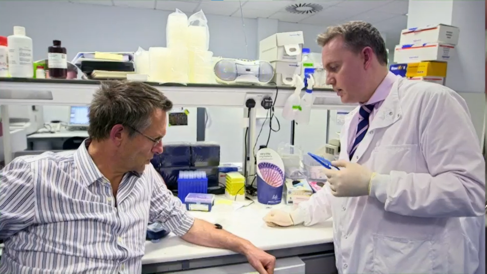 a man in a lab coat is talking to another man