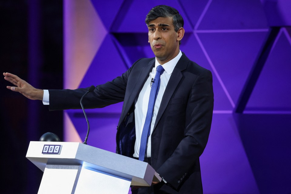 a man in a suit and tie stands at a bbc podium