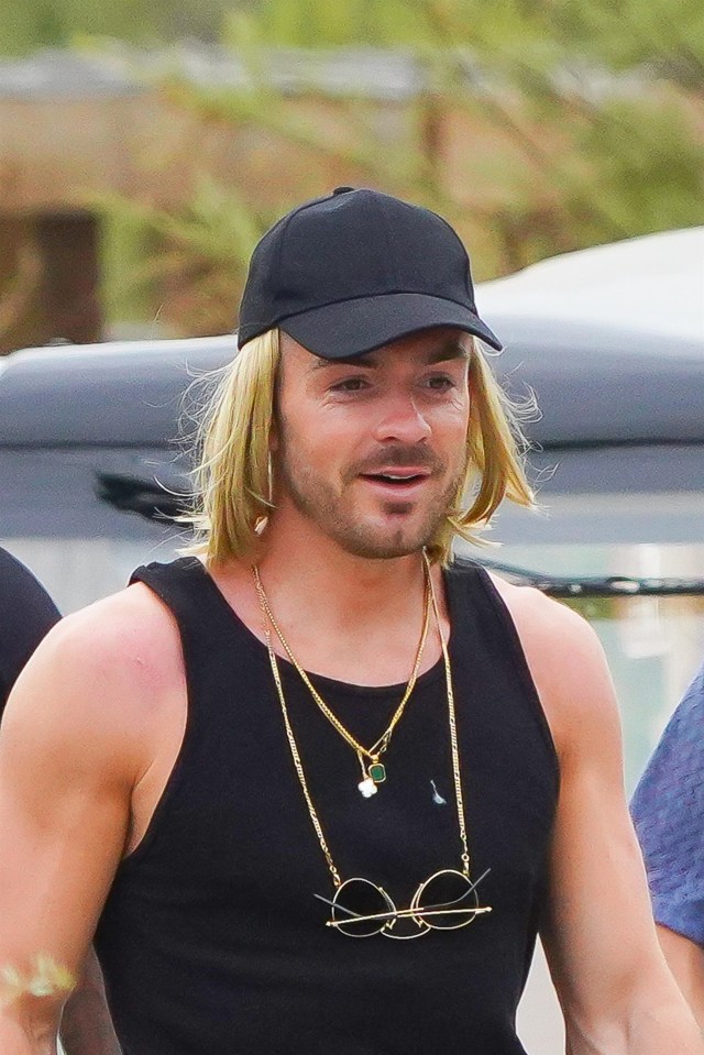 He tucked the blond locks under a black cap and wore a tank top, shorts and sliders