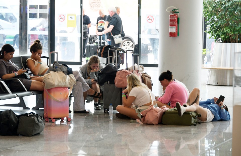 Passengers sit on the ground after delayed flights from Majorca