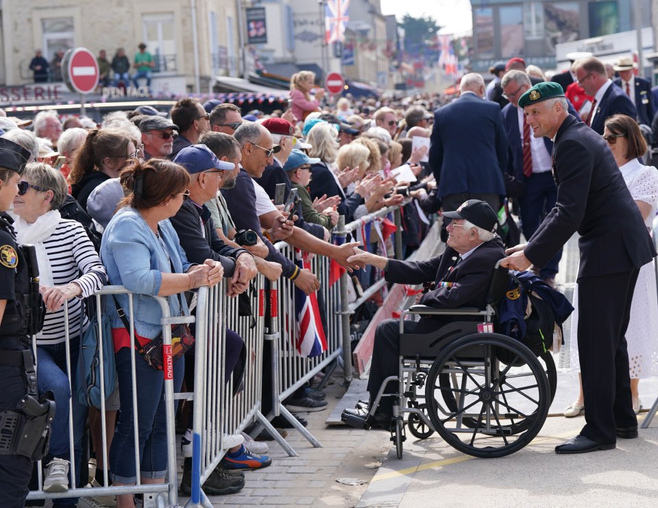 An old soldier is clapped and greeted by the crowd