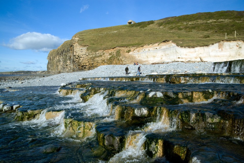 The Welsh beach is backed by a dramatic cliff and the nearby Nash Brook overflows onto a rock platform that create gushing waterfalls