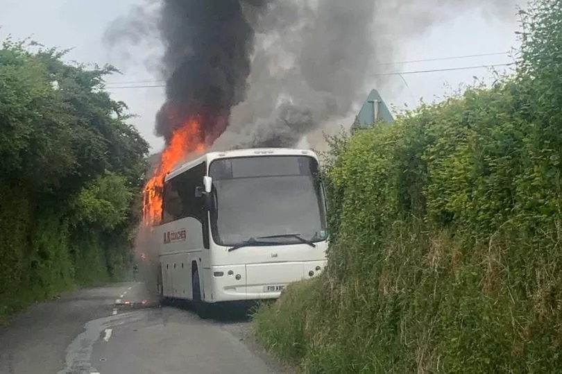 Flames can be seen pouring from the back of the school bus