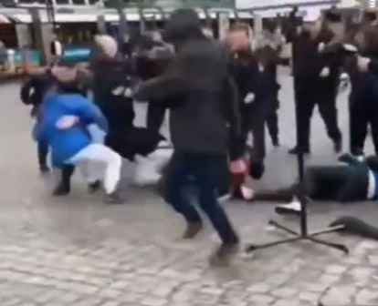 A cop tackles the man in blue to the ground