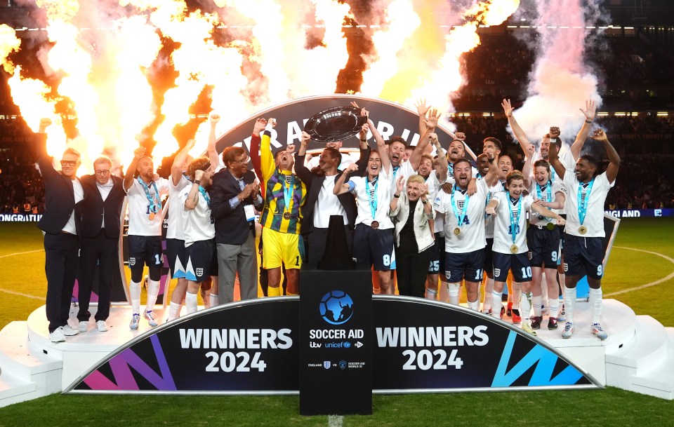 England players and coaches celebrate with the trophy following victory in Soccer Aid for Unicef at Stamford Bridge in 2024