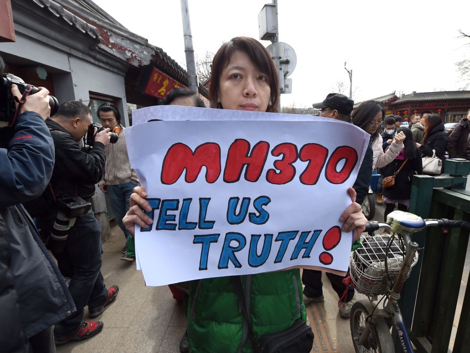 A family member of a Chinese passenger from the missing Malaysia Airlines flight MH370 holds up a poster in protest, 2015