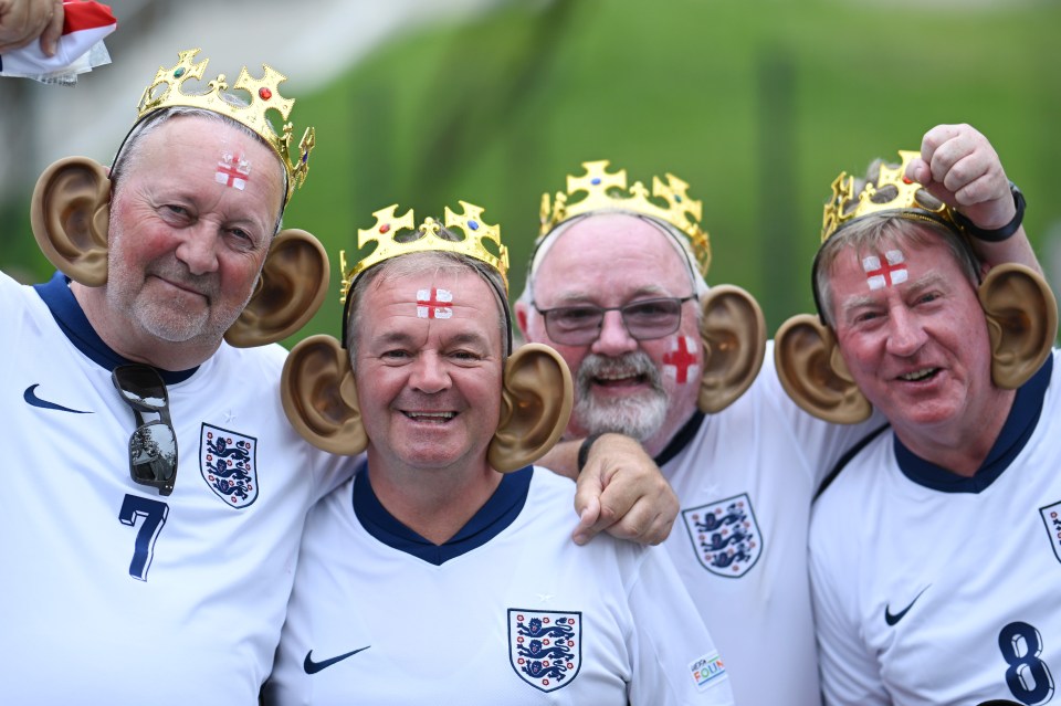 Fans of England pose for a photo while wearing replica crowns and big ears