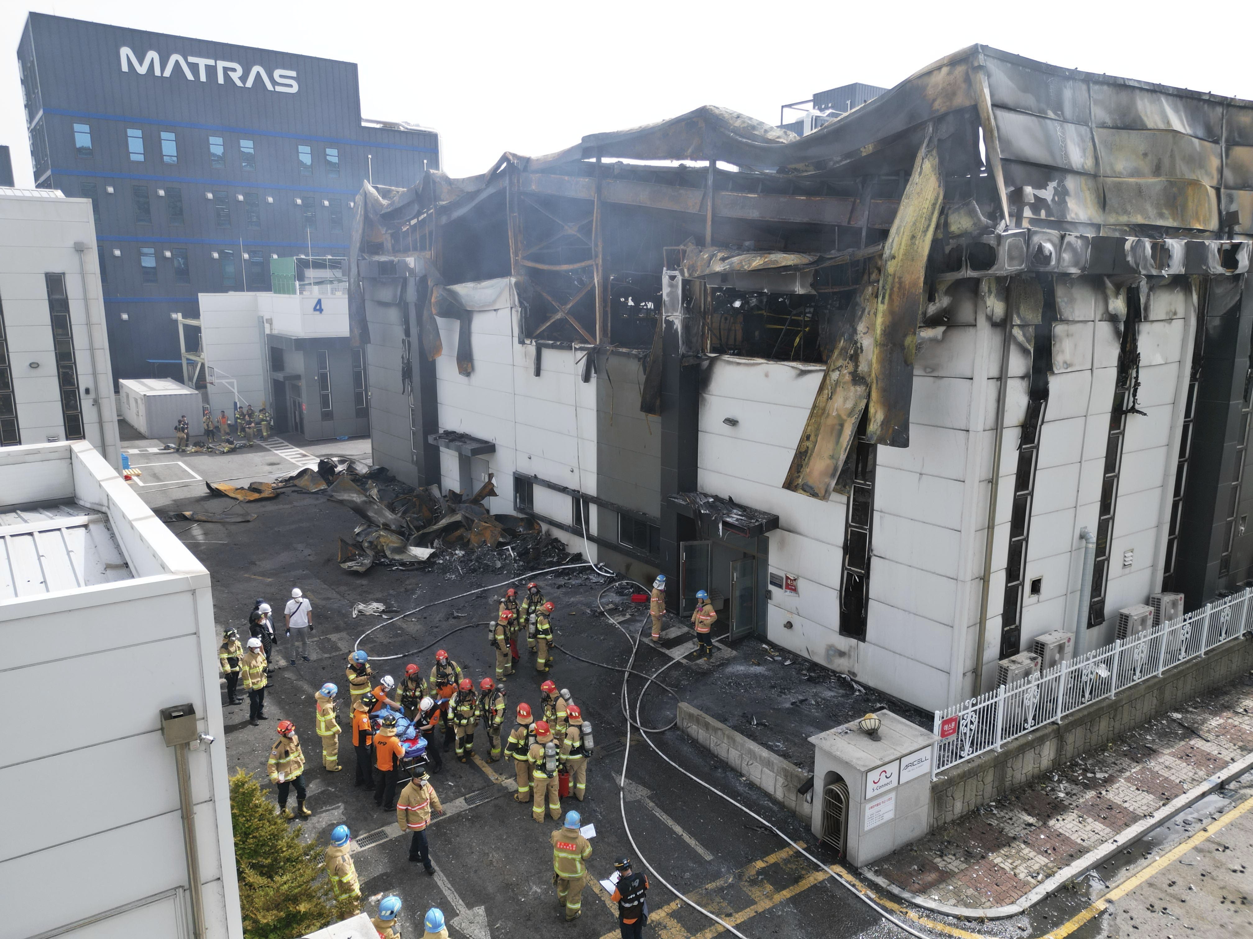 Fire officials gathered outside the collapsing factory after the devastating fire Credit: AP