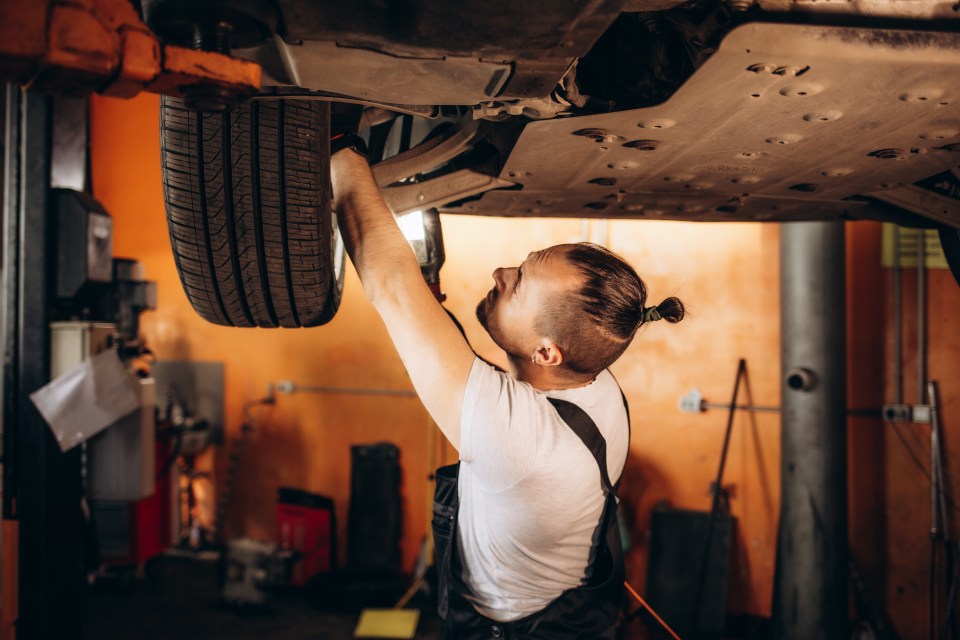 a man is working under a car with a tire on it