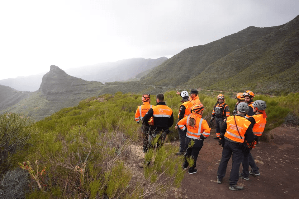 a group of people standing on top of a mountain wearing jackets that say rescue