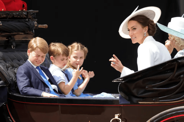 a woman in a white hat talks to three children in a carriage