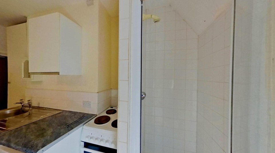 The small apartment has a shower just inches away from a cooking hob