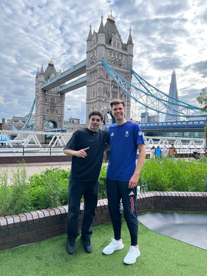 two men are posing for a picture in front of the tower bridge