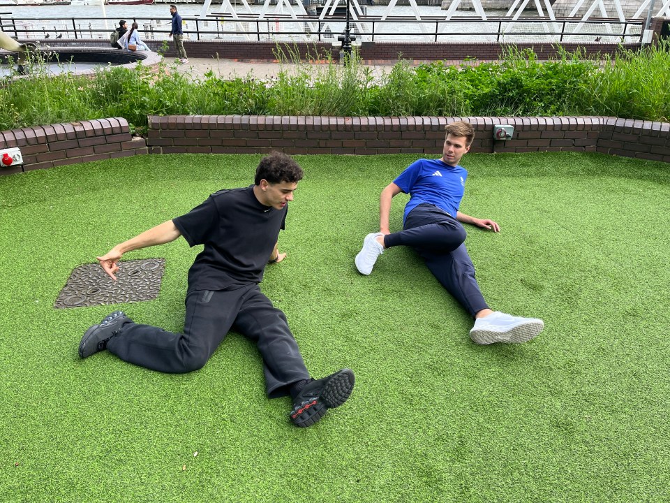 a man in a blue adidas shirt sits on the grass