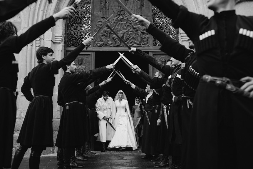 a black and white photo of a bride and groom holding swords