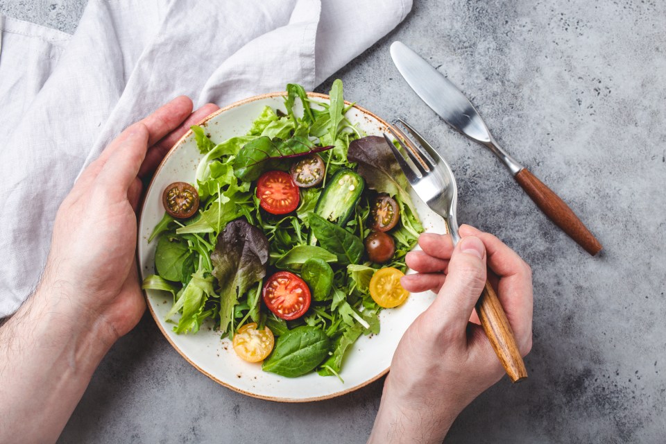 a person is eating a salad with tomatoes and lettuce