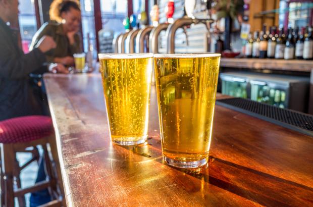 Two pints of lager on a pub bar.