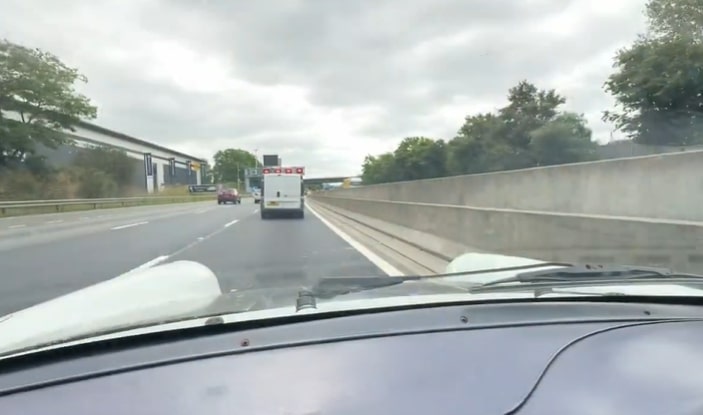 a white van is driving down a highway with a sign that says ' toyota ' on it