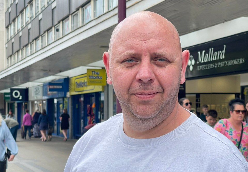 a bald man stands in front of a mallard store