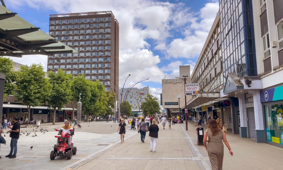 people walking down a street in front of a building that says eastgate