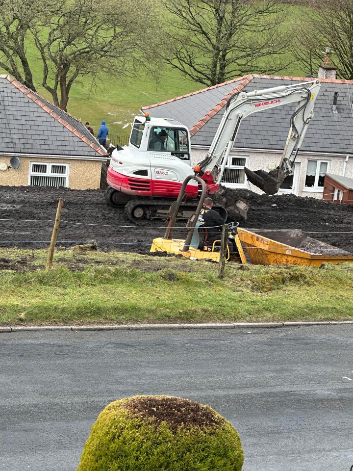 A digger removes earth in full view of the houses