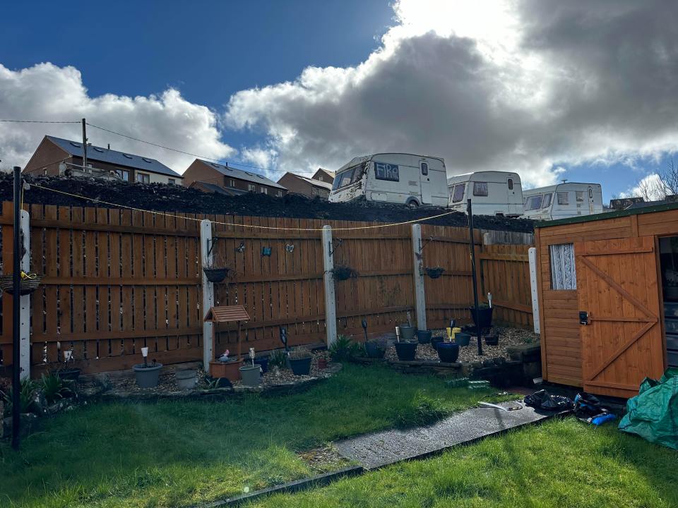 The view from a garden of one of the houses shows the precarious position of the caravans