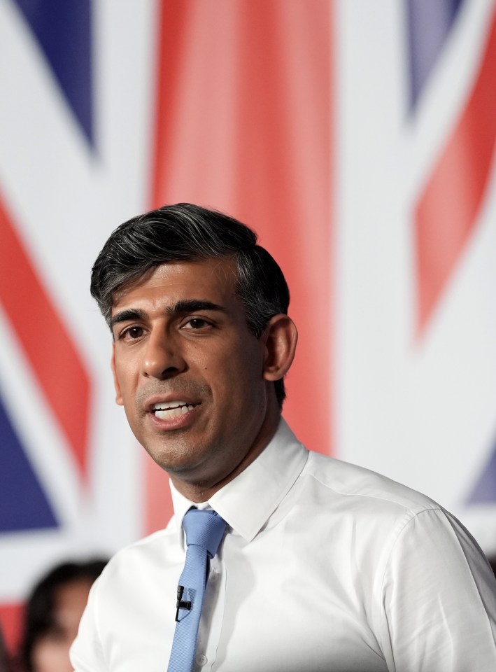 a man in a white shirt and blue tie stands in front of a british flag