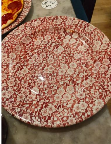 a red and white plate with a floral pattern is sitting on a table .