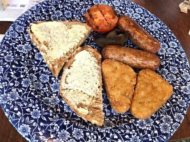 a plate of food with a tomato and sausage on it