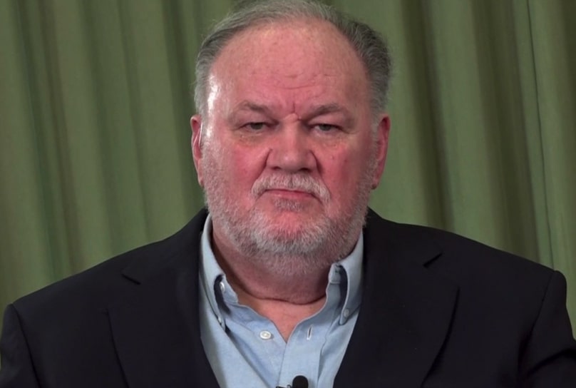 a man with a beard is wearing a suit and a blue shirt