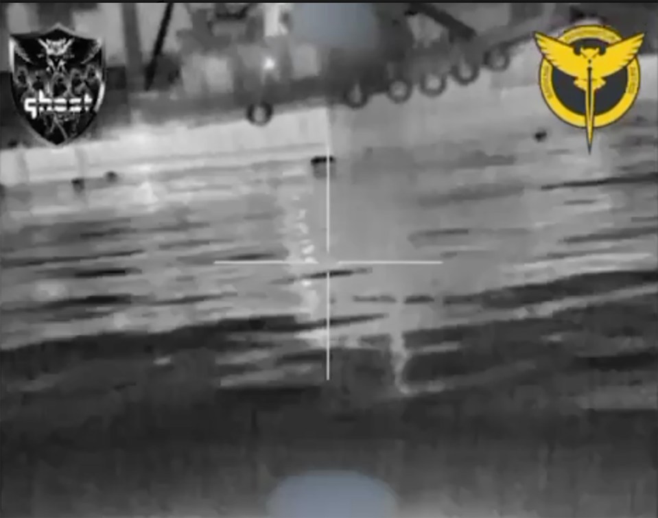 The shadowy figure of a tugboat crew member is seen in black and white video