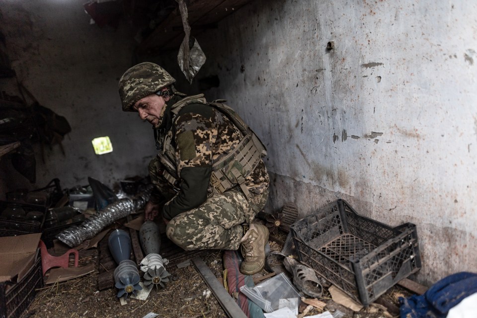 A Ukrainian soldier prepares mortar shells at his fighting position